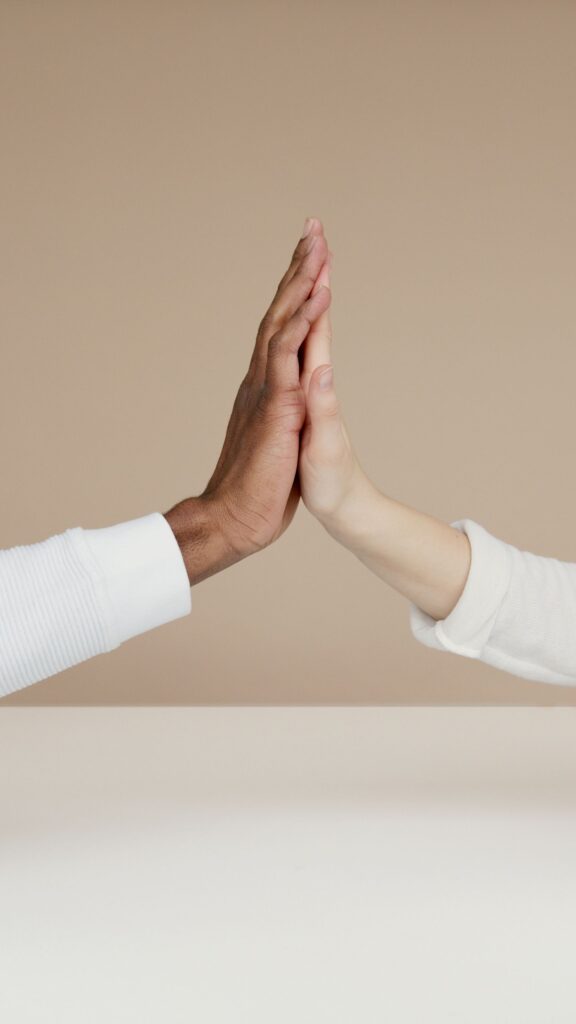 Two hands meet in a high-five, symbolizing cooperation and unity.